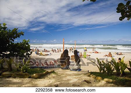 Stock Photo - Brazil, Bahia State, Itacare, People sitting on beach. Fotosearch