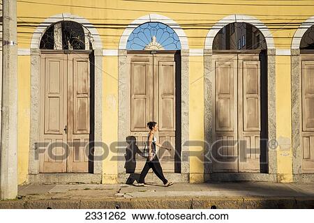 Stock Image - Brazil, Rio Grande do Sul, Praca General Osorio; Pelotas, Young woman walking on street. Fotosearch
