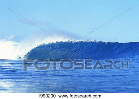 Stock Image - Breaking Wave, Sprays Of Water Off Lip, Textured Face, Blue Skies.. Fotosearch