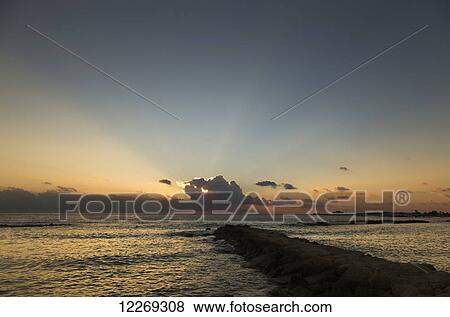 Breakwater leading out to the ocean with a sunset over the water; Paphos, Cyprus View Large Photo Image Stock Photo - Breakwater leading out to the ocean with a sunset over the water; Paphos, Cyprus. Fotosearch