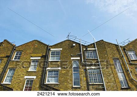 Picture - Brick residential buildings with pipes going up the wall and antenna on the roof; London, England. Fotosearch
