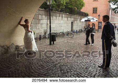 Bride Posing For Photograph With Groom Watching; Stockholm Sweden View Large Photo Image Picture - Bride Posing For Photograph With Groom Watching; Stockholm Sweden. Fotosearch