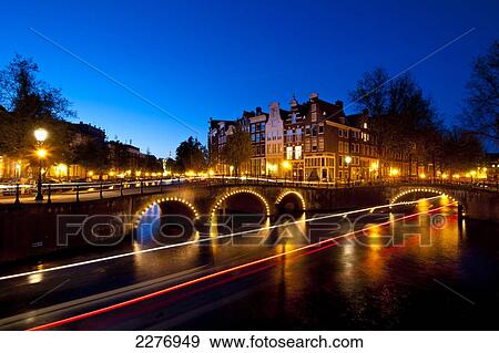 Bridges over canals at dusk with streak of lights from boat; Amsterdam, Holland View Large Photo Image Stock Photo - Bridges over canals at dusk with streak of lights from boat; Amsterdam, Holland. Fotosearch