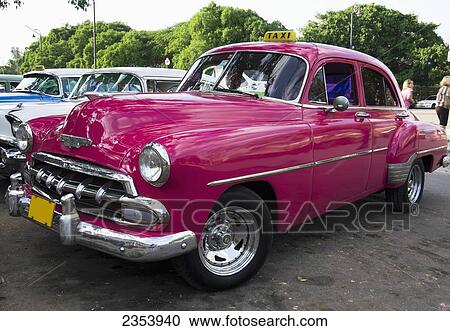 Stock Image - Bright Pink Chevy Taxi Parked With Other Taxis; Havana, Artemisa, Cuba. Fotosearch