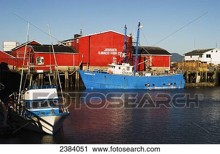 Stock Image - Bright red building and blue boat in the Port of Ilwaco; Ilwaco, Washington, United States of America. Fotosearch