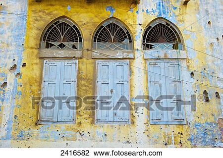 Stock Image - Broken windows and old shutters on a weathered and worn building; Beirut, Lebanon. Fotosearch