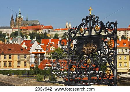 Stock Image - Bronze Relief On Charles Bridge Or Karluv Most With Royal Palace In The Background; Prague Czech Republic. Fotosearch