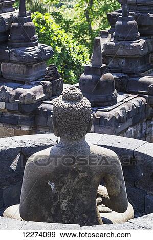 Buddha statue amidst the latticed stone stupas containing Buddha statues on the upper terrace, Borobudur Temple Compounds, Central Java, Indonesia View Large Photo Image Stock Photo - Buddha statue amidst the latticed stone stupas containing Buddha statues on the upper terrace, Borobudur Temple Compounds, Central Java, Indonesia. Fotosearch