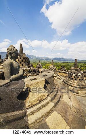 Buddha statue with the hand position of dharmachakra mudra amidst the latticed stone stupas containing Buddha statues on the upper terrace, Borobudur Temple Compounds, Central Java, Indonesia View Large Photo Image Stock Photography - Buddha statue with the hand position of dharmachakra mudra amidst the latticed stone stupas containing Buddha statues on the upper terrace, Borobudur Temple Compounds, Central Java, Indonesia. Fotosearch