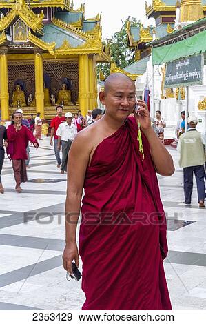 Stock Photo - Buddhist Monk With Camera Talking On A Cell Phone; Yangon, Myanmar. Fotosearch