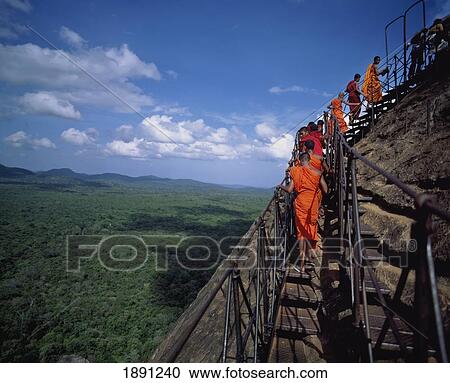 Stock Image - Buddhist Monks Climbing Steps Of Sigiriya Lion Rock Fortress. Fotosearch