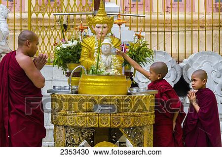 Stock Image - Buddhist Monks Pour Water Over A Buddha Statue In A Temple; Yangon, Myanmar. Fotosearch