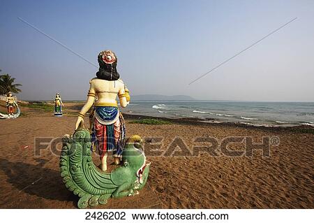 Stock Image - Buddhist statues on the beach at the water's edge; Visakhapatnam, Andhra Pradesh, India. Fotosearch