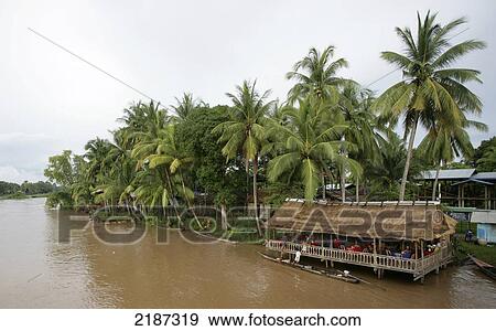 Stock Photo - Building filled with people along the Mekong River; Don Det Island, Champasak Province, Laso. Fotosearch