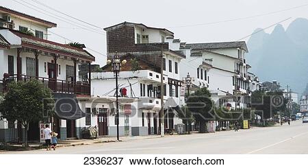 Buildings Along A Street With Pedestrians And Mountain Peak In The Distance; Guilin, Guangxi, China View Large Photo Image Stock Photo - Buildings Along A Street With Pedestrians And Mountain Peak In The Distance; Guilin, Guangxi, China. Fotosearch
