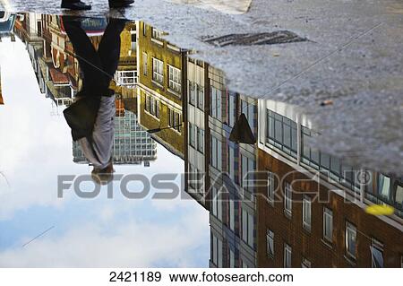 Buildings and a pedestrian reflected in a water puddle in the street, Soho; London, England View Large Photo Image Stock Photo - Buildings and a pedestrian reflected in a water puddle in the street, Soho; London, England. Fotosearch