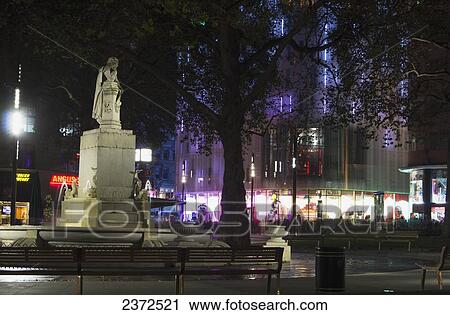 Stock Image - Buildings and a statue illuminated at night; London, England. Fotosearch