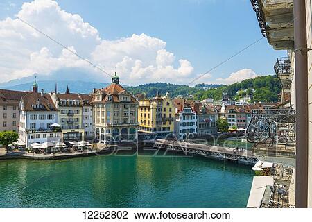 Stock Image - Buildings and bridge crossing River Reuss; Lucerne, Switzerland. Fotosearch