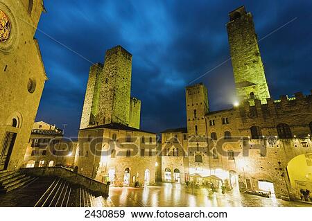 Stock Photo - Buildings illuminated by golden lights at dusk; San Gimignano, Tuscany, Italy. Fotosearch