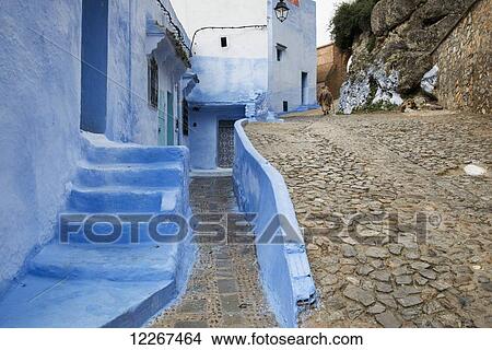 Buildings painted blue with woman walking up cobbled slope; Chefchaouen, Morocco View Large Photo Image Picture - Buildings painted blue with woman walking up cobbled slope; Chefchaouen, Morocco. Fotosearch