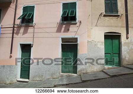 Picture - Buildings with green doors and shutters line the street; Riomaggiore, Liguria, Italy. Fotosearch