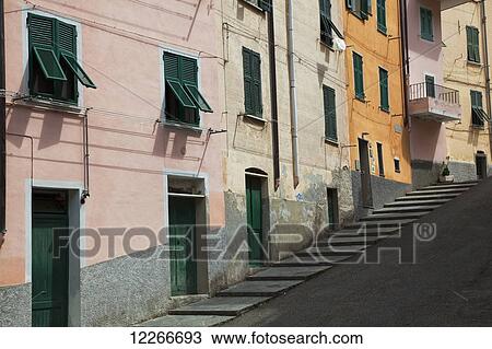 Stock Image - Buildings with green doors and shutters line the street; Riomaggiore, Liguria, Italy. Fotosearch