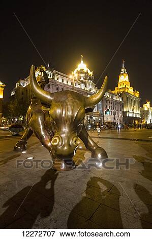 Stock Photo - Bund Bull sculpture, a derivative of Arturo Di Modica's Charging Bull, on the Bund at night, Shanghai, China. Fotosearch
