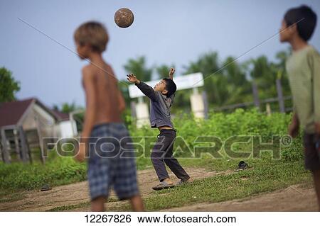 Stock Photograph - Bunong boys playing volleyball; Mondulkiri, Cambodia. Fotosearch
