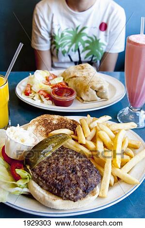 Stock Image - Burger and chips in a dinner, the traditional America meal; Manhattan, New York, United States of America. Fotosearch
