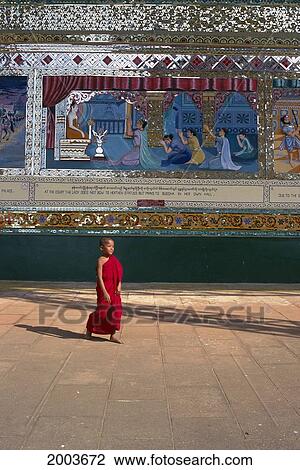 Stock Image - Burma (Myanmar), View Of Monk Walking By Painted Reliefs Temple Courtyard. Fotosearch