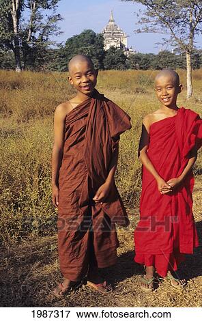 Stock Photo - Burma, Old Bagan, Two Young Buddist Monks On Dry Grassy Road, Temple In Distance. Editorial Use Only.. Fotosearch