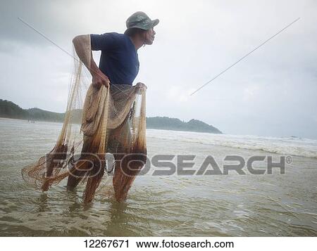 Stock Image - Burmese fisherman on Thai beach; Ranong, Thailand. Fotosearch