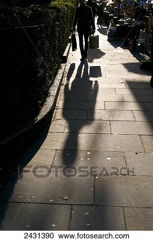 Stock Image - Businessman walking on Portobello Road at sunrise; London, England. Fotosearch