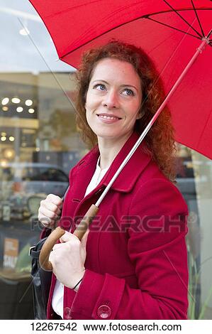 Stock Image - Businesswoman holding a red umbrella; Abbotsford, British Columbia, Canada. Fotosearch