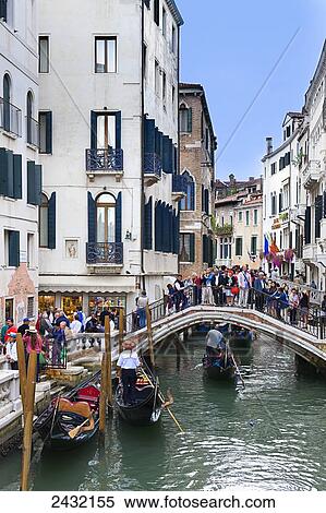 Stock Photography - Busy area around the canal with a footbridge filled with pedestrians; Venice, Italy. Fotosearch