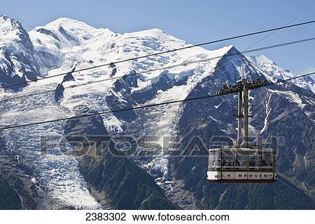 Stock Image - Cable car heading to Le Brevent, above Chamonix-Mont Blanc valley, with Mont Blanc mountain in background; France. Fotosearch