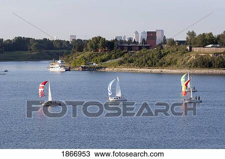 Stock Image - Calgary, Alberta, Canada; Sailboats On The Water With Heritage Park And The City In The Background. Fotosearch