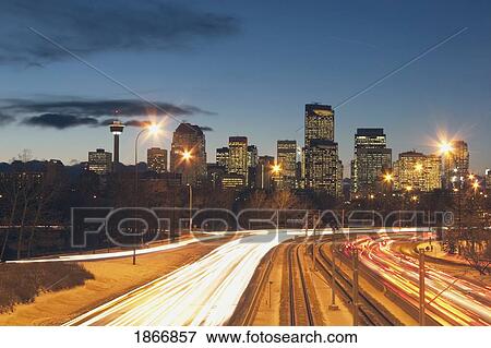 Stock Photo - Calgary, Alberta, Canada; Skyline At Night With Car Lights On The Road. Fotosearch