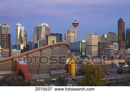 Stock Photo - Calgary Skyline With The Saddledome Calgary Tower And Buildings At Dawn With Deep Blue Sky And Magenta Clouds; Calgary Alberta Canada. Fotosearch