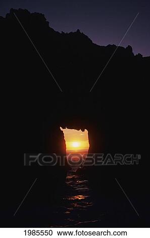 Stock Image - California, Big Sur Coast, Pfeiffer Beach, Sunset Over Ocean, Framed By Archway In Silhouetted Rock.. Fotosearch
