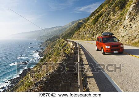 Stock Image - California, Big Sur, Coastal Shot Of Highway 1 With Red Vehicle Driving. Fotosearch