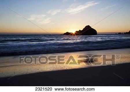 Stock Image - California, Big Sur, Pfeiffer Beach, Sun Setting Over Pacific Ocean.. Fotosearch