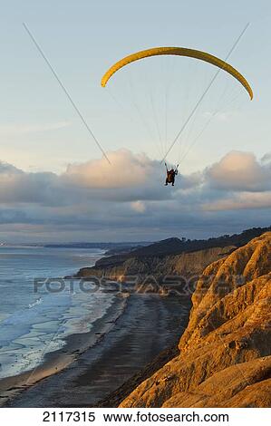 Stock Photography - California, La Jolla, Paraglider flying over ocean cliffs at sunset. EDITORIAL USE ONLY.. Fotosearch