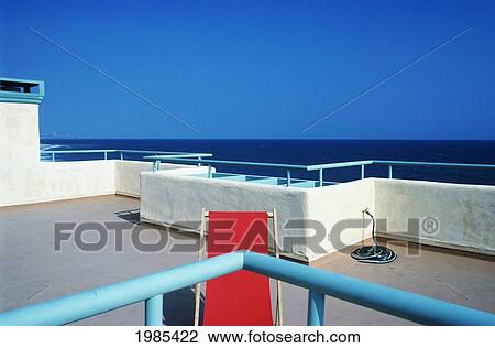 Stock Image - California, Malibu, Chair On Rooftop Overlooking Blue Ocean On Beautiful Sunny Day.. Fotosearch