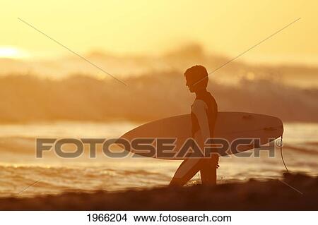 Picture - California, San Clemente, Surfer Walking Towards Ocean At Sunset. Editorial Use Only.. Fotosearch