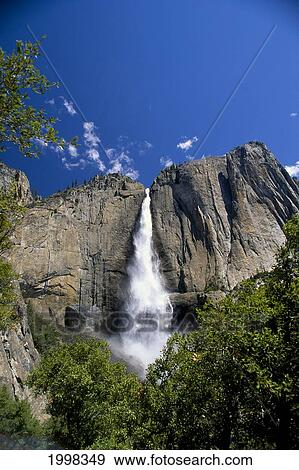 Stock Photo - California, Yosemite National Park, Upper Falls Come Down Rocks, Blue Skies B1643. Fotosearch
