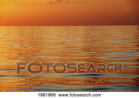 Stock Photograph - Calm Sea Surface With Orange Sunset, Low Angle View. Fotosearch