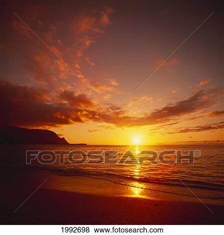 Stock Photo - Calm Shoreline Ocean Waters With Orange Reflections From Sunset, Dark Orange Clouds.. Fotosearch