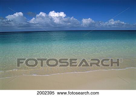 Stock Photography - Calm Shoreline Water With Many Different Shades Of Blue, Clouds Above Horizon. Fotosearch