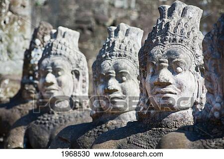 Stock Image - Cambodia, Angkor, Angkor Thom, Weathered Statues Line The Entrance To The Ancient City.. Fotosearch